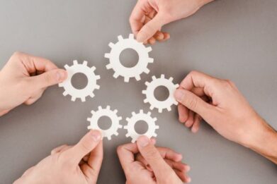 cropped view of people holding white gears on grey background
